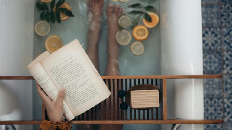 Person reading in a serene bath with citrus and soap, perfect for a self-care retreat.