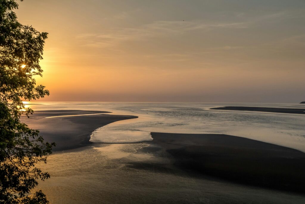 Beautiful sunset at Le Mont-Saint-Michel in Normandy, France showcasing low tide and serene ocean views.