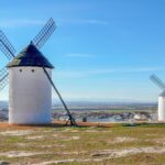 Iconic white windmills in Campo de Criptana, Spain, set against a clear sky.