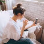 Woman sitting on a cozy sofa having a video call, enjoying a relaxed moment at home.