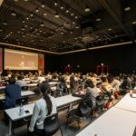 A diverse group attending a conference in a modern hall in Gwangju, South Korea.