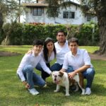 A family posing with a bulldog in a sunny garden setting.